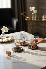 INVOKE copper banded clear glass shot glasses with wooden coasters and lemon garnish.