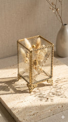 INVOKE decorative glass makeup brush holder with antique brass frame and ornate feet, holding dried flowers.