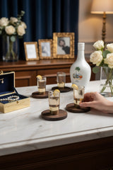 INVOKE Cabo White Rum With Coconut Liqueur bottle and shot glasses with lemon garnish on a marble bar.