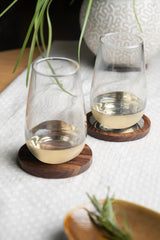 INVOKE Clario High Ball Glass with tapered design and substantial base, made of clear glass. Set on wooden coasters.