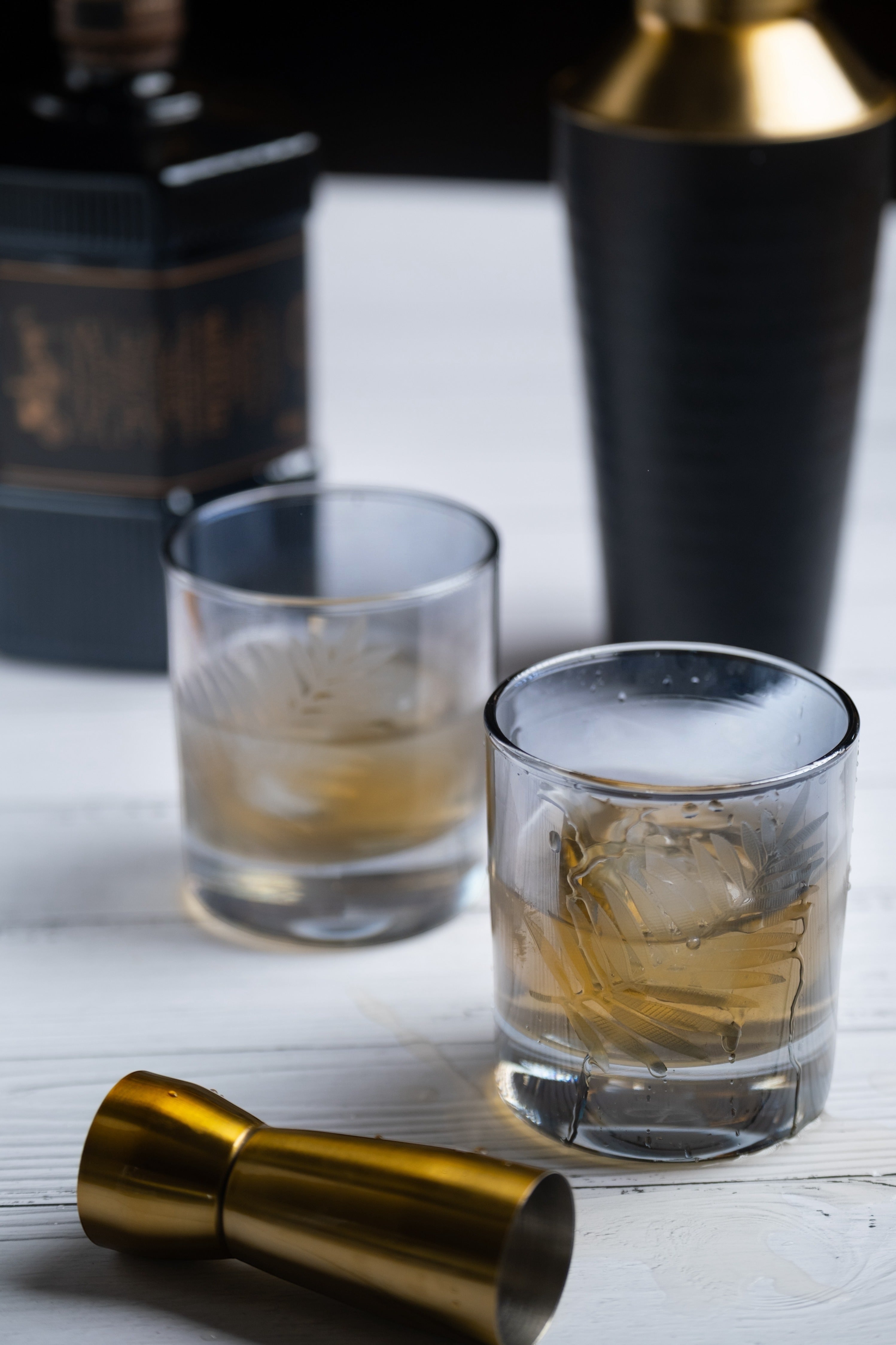 INVOKE Etched Leaf Pattern Lowball Whiskey Glasses Set with ice and whiskey.