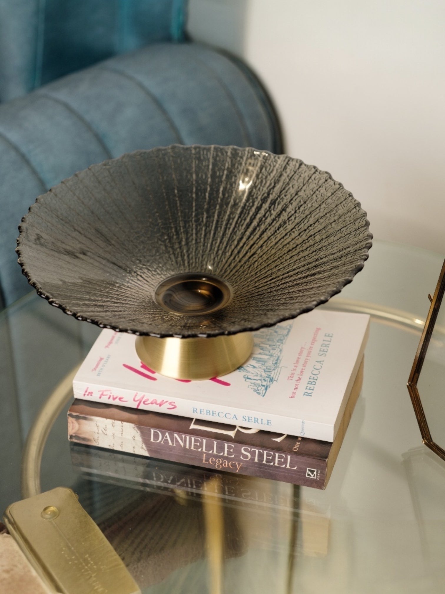 Invoke Home and Living large round textured smoky grey glass platter with brushed gold base, displayed on books.
