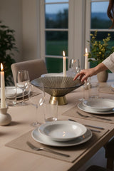 Invoke Home and Living large textured smoky glass round platter with brushed gold base, set on a dining table.